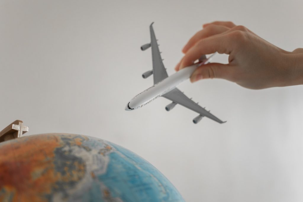 Mano con un aeroplano in miniatura sopra un mappamondo